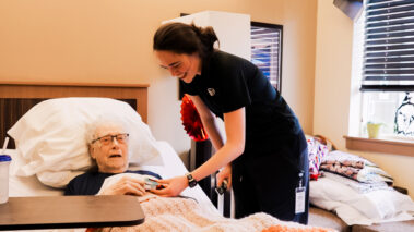 woman helping resident in bed