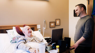 man helping resident in bed