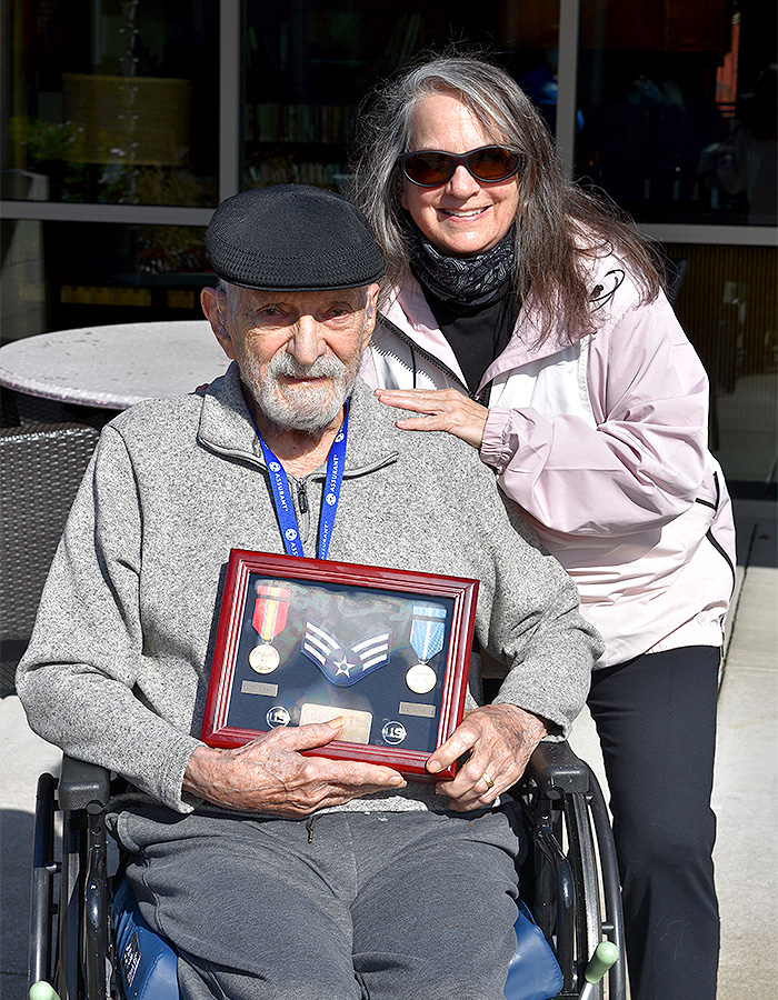 VCCO Employee smiling with veteran who is holding their medals